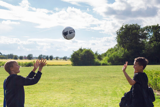 Two boys (12-13) throwing soccer ball in field
