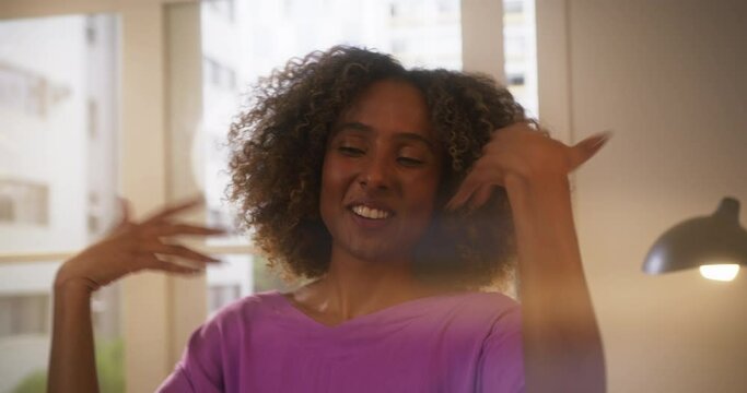 Portrait of Young Black Woman Having Fun and Dancing with Friends to Music at Home in Cozy Sunny Living Room. Beautiful Female with Curly Hair Enjoying Summer Vacation Party. Slow Motion