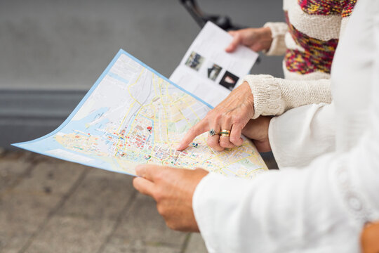 Mid section of two senior women holding map