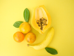 papaya fruit, oranges and banana yellow  background
