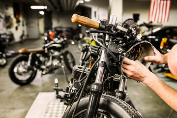 Man repairing motorcycle headlight in workshop