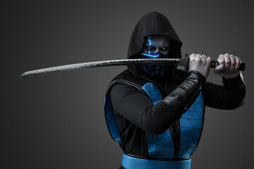 Portrait of Ice assassin dressed in costume with hood posing with katana. © Fxquadro