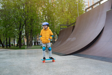 a child rides a blue city cruiser, a plastic bright skateboard, in a skate park on a halfpipe	