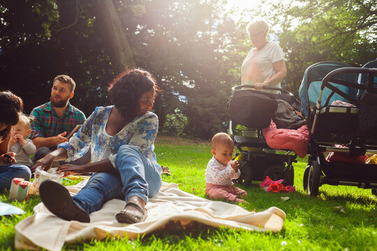 Family with children (6-11 months, 2-3, 6-7) having picnic in park
