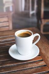 Hot black coffee in a white mug on a wooden table.