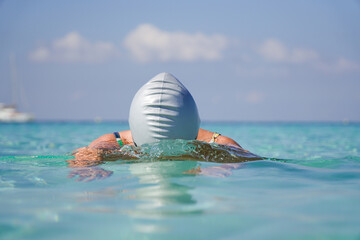 a woman swimmer on summertime vacation in the sea with a swim cap