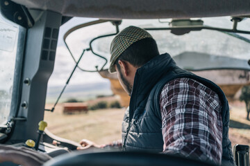 Young farmer in beret maneuvering his tractor in reverse in the field. © Jorge