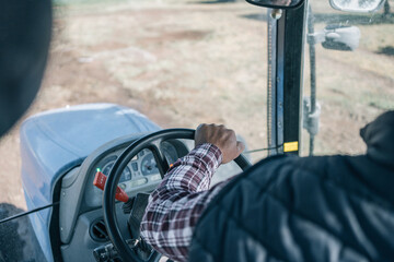 POV image of a young farmer's hand maneuvering his tractor backwards across the field.