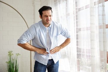 young man having a stomach ache from food poisoning at home