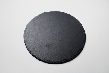 Black round stone slate plate on gray paper background.