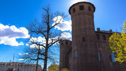 Medieval tower of Palazzo Madama in the middle of Piazza Castello packed with people on a sunny spring afternoon