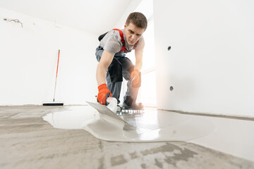 Leveling with mixture of cement for floors. Worker use screed concrete epoxy for level