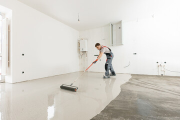 Worker use screed concrete epoxy for level. Leveling with mixture of cement for floors