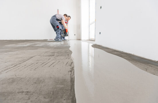 Leveling with mixture of cement for floors. Worker use screed concrete epoxy for level