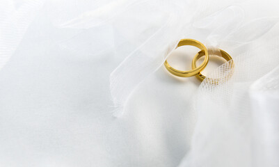 Gold wedding rings with ribbon tied on white fabric