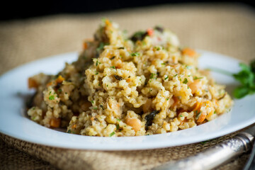 cooked bulgur with vegetables, carrots and dried mushrooms in a plate .