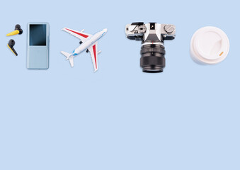 Travel flatlay. Headphones, mp3 player, camera, plane and  coffee on blue background with copy space. planning summer vacation concept. Summer workspace.