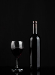 Red wine bottle and glass on dark background