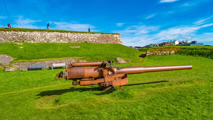 Fototapeta premium Torshavn, Faroe Islands - Lighthouse, old military fortress Skansin with cannons, WWII guns and tourists in the modern capital Torshavn of Faroe islands