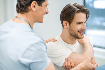 Fototapeta premium Manual therapist helping patient to work out the shoulder joint