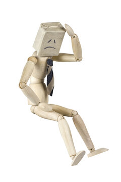 Wooden mannequin wearing a paper bag with a sad face and a necktie depiction of a sad businessman  