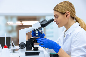 Blonde scientist working with microscope, analyzes petri dish sample, specialists works on medicine