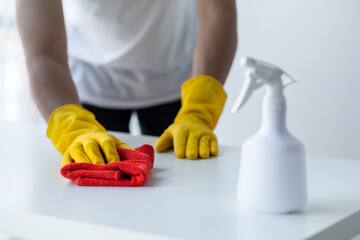 Person cleaning the room, cleaning staff is using cloth and spraying disinfectant to wipe the table in the company office room. Cleaning staff. Maintaining cleanliness in the organization.