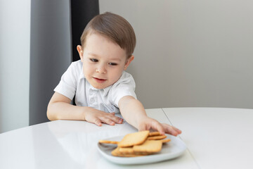 The concept of children and sweets. Cute little boy craves cookies, sweet tooth