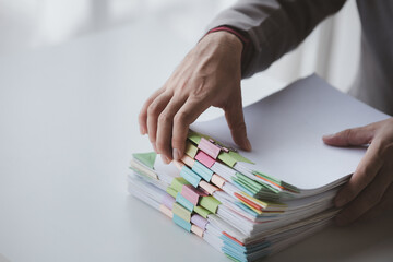 Person with stacks of company financial report papers in office, company employee picking up papers...