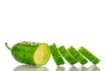 One ripe cucumber gherkin cut into slices, macro, isolated on white background.