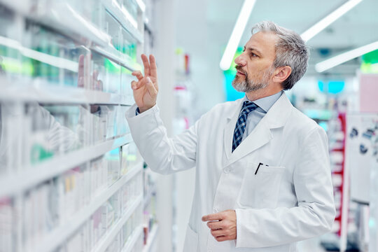 An expert male pharmacist looking for a medicine for a patient in the drugstore.