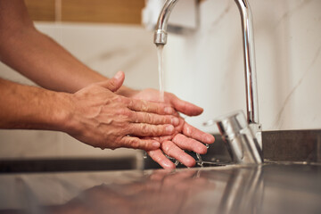 A cooking male chef washing his hands before starting to prepare food.