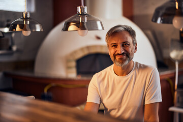 Portrait of a male pizza master, preparing pizza for the oven in the kitchen.