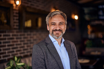 Portrait of a smiling owner of a small business, standing in his restaurant.