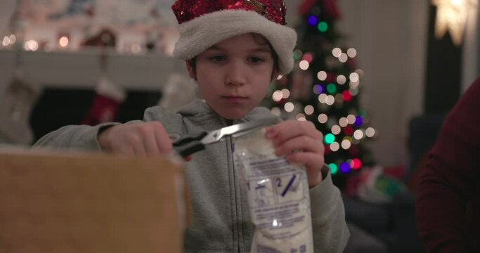 Young boy opens icing for gingerbread house building at christmas time