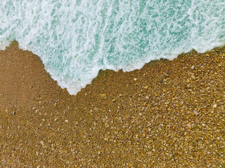 Top view of the sandy beach and the incoming wave.