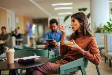 Fotobehang Kruidenier Businesswoman eating lunch in cafeteria.  © bernardbodo