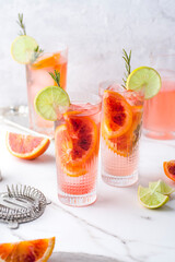 Light cocktail with lime juice and blood orange flavored with rosemary on a marble table. Summer...