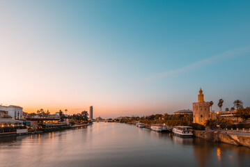 Fototapeta na wymiar Seville's Iconic Landmarks at Blue Hour: Guadalquivir River, Triana District and Giralda Tower