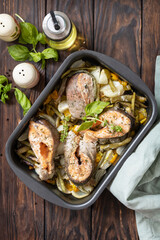 Low carb dinner, healthy nutrition concept, diet menu. Healthy baked fish salmon steaks with basil, green beans and sweet peppers on a rustic table. View from above.