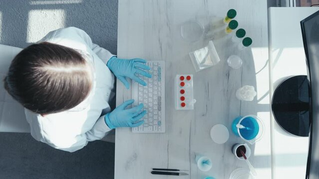 Keyboard and computer screen in the focus of a video clip demonstrating data entry and analysis of research results by a researcher in medicine, biology and chemistry. Top view of the camera.