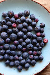 Turquoise plate with fresh blueberries on wooden background. Top view.