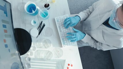 Analysis of scientific research data in the laboratory in order to identify new trends and predict future results. A scientist sits at a monitor and types on a keyboard. Medical worker at the table. - Powered by Adobe