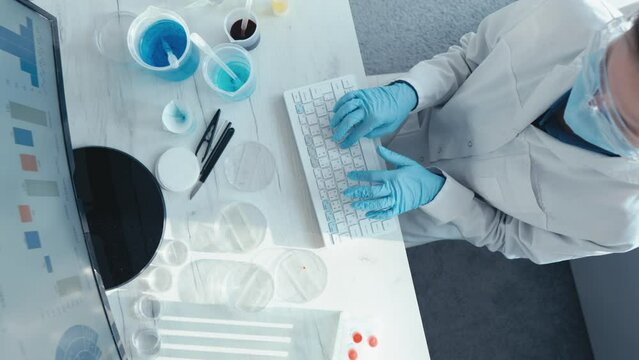 Analysis of scientific research data in the laboratory in order to identify new trends and predict future results. A scientist sits at a monitor and types on a keyboard. Medical worker at the table.