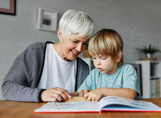 grandchild family child grandparent grandmother book reading elderly grandson boy happy together...