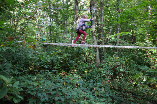 Petite fille sur un parcours d'acrobranche dans une for&ecirc;t