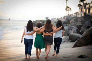Four female friends walking on a beach together