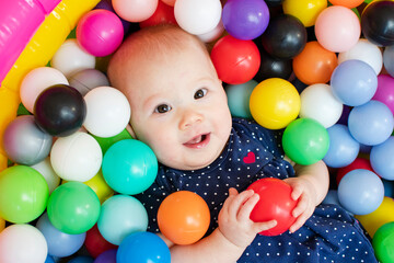 Fototapeta na wymiar Portrait of a Caucasian baby happy face. Healthy baby in the ball pit playing with colorful plastic balls. 