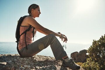 Stopping to regain some energy. a young woman taking a break while out on a hike through the...