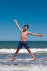 Happy boy performs pirouettes and big jumps on the seashore during his summer vacation on the...